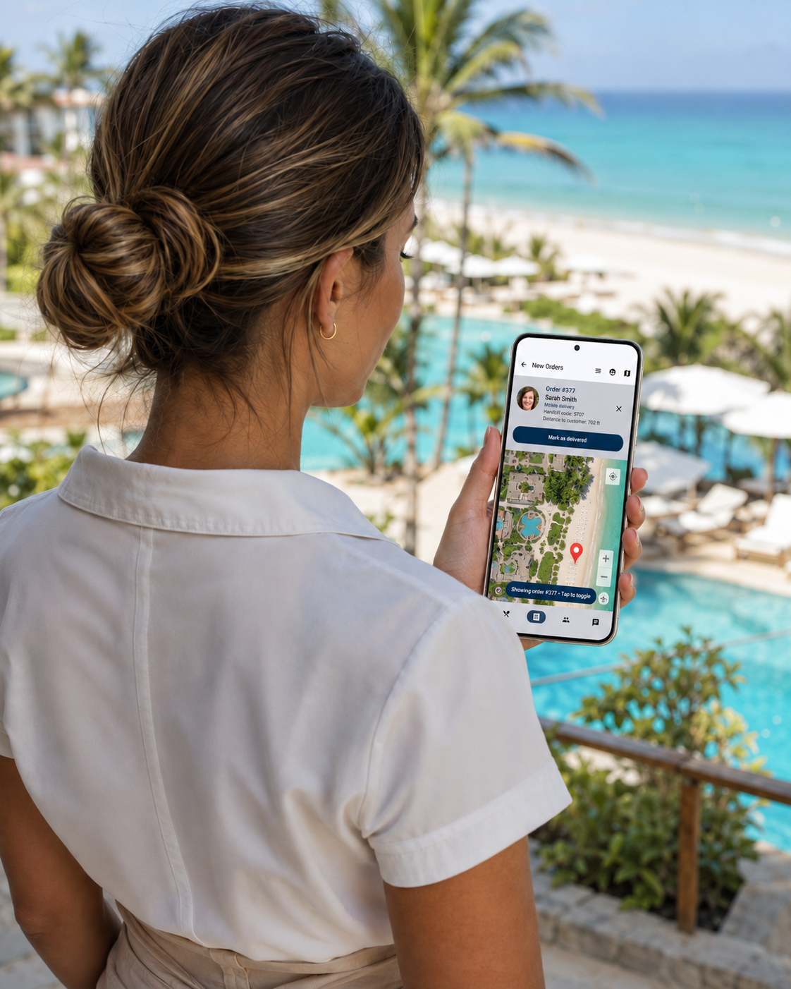 Resort server checking a delivery order on a map, overlooking the pool and beach